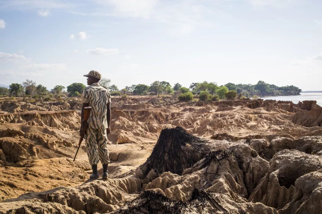 A guide crossing eroded riverbank terrain