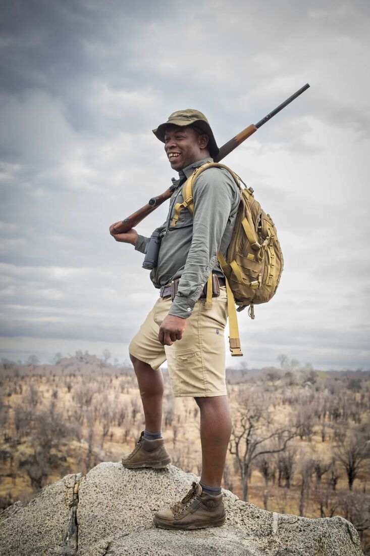A guide with a rifle on a granite kopje during a walking safari